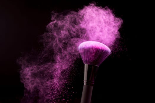 makeup brush with purple powder dust dark background. High resolution photo