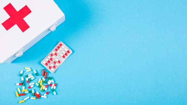 overhead view first aid kit with colorful capsules blue background. High resolution photo