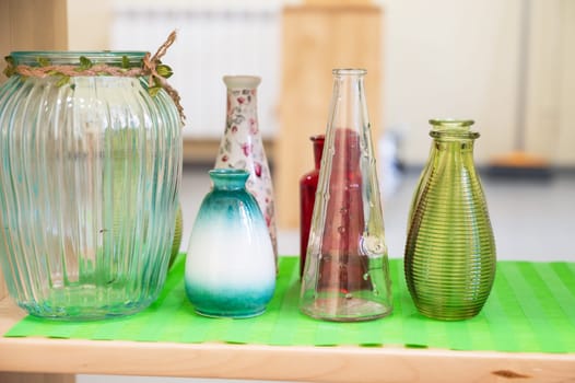 Assorted decorative glass and ceramic vases in various shapes and colors displayed on a green mat, creating a rustic aesthetic.