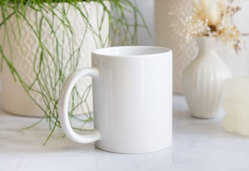 White ceramic coffee mug on white marble near potted green plants Close up. Mock up in scandinavian style. Subject template for your design, advertising with copy space