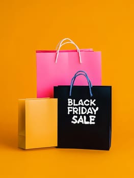 A collection of shopping bags with Black Friday sale messages, set against a bright orange background for retail promotions.