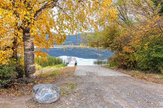 Trees with yellow leaves layer over the ramp to the dock on McArthur Lake in north Idaho.
