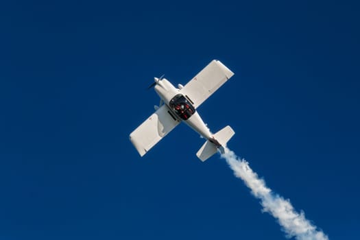 Stunt aerobatic plane inverted flying performing stunts in blue sky. Concept of speed, difficulty, precision, risk, challenge