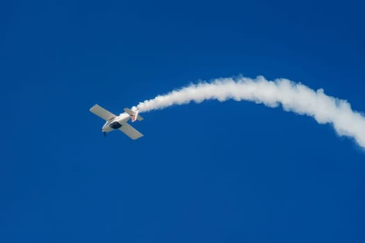 Stunt aerobatic plane inverted flying performing stunts in blue sky. Concept of speed, difficulty, precision, risk, challenge