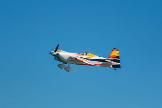 Stunt aerobatic plane performing stunts in blue sky. Concept of speed, difficulty, precision, risk, challenge