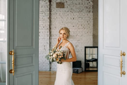 The stunning bride with her exquisite bouquet exudes grace and elegance in a beautifully decorated room at the open doors