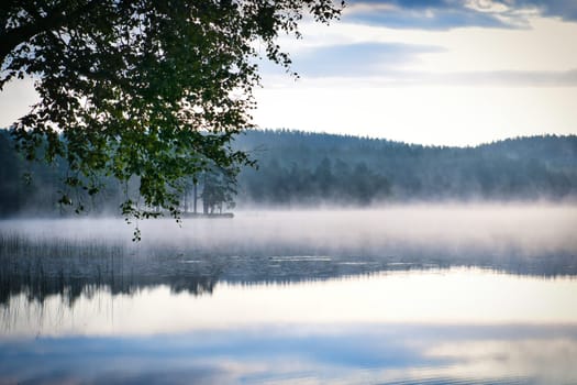 Fog forming over a lake in Sweden at dawn. Romantic silence, in the Scandinavian nature