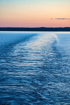 View from a ship departing from an island on the sea at sunset. Scandinavian nature