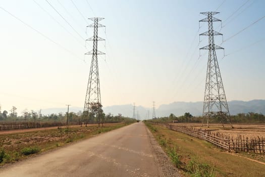 On the Thakhek Motorbike Loop in dry season, the road runs through dried out farmland next to high electricity poles, Laos 2023
