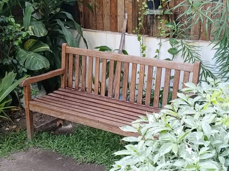A charming garden area with rustic wooden benches and a table surrounded by lush greenery, creating a peaceful and inviting outdoor space.
