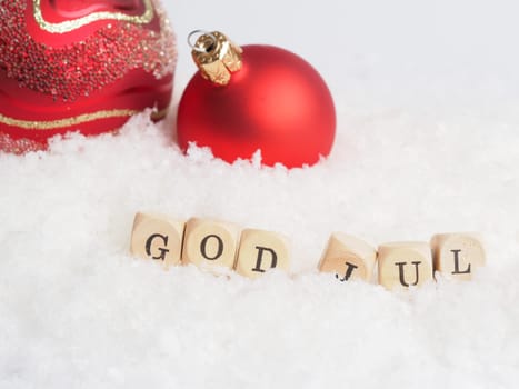 Red Vintage Christmas baubles with wooden blocks and the words God Jul, Scandinavian Merry Christmas in snow