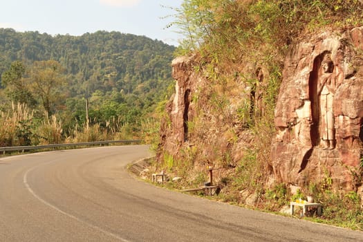 The windy, winding road leads along some Sandstone Buddha Rock Sculptures on the Thakhek Motorbike Loop, Laos 2023