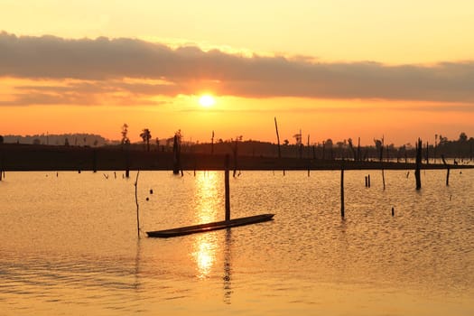 Watching the sunset over the flooded forest, trees, reservoir lake of Nam Theun, a boat is tied to one of the dead trees, village of Thalang, Thakhek Motorbike Loop, Laos 2023