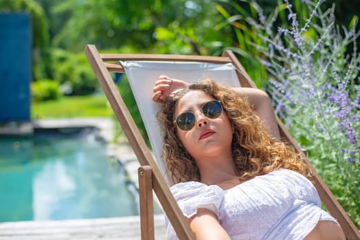 relaxed young woman with sunglasses lying in a deck chair