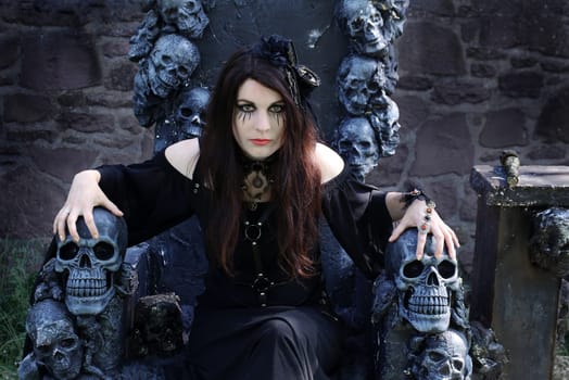 Fantasy photo with an evil witch on a throne with skulls