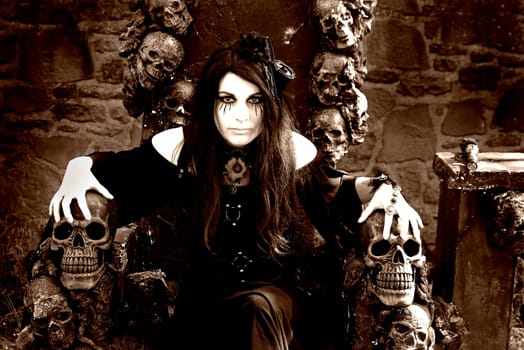Fantasy photo with an evil witch on a throne with skulls