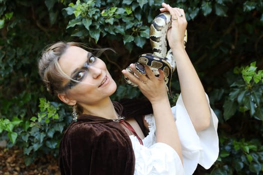 A woman dressed as a witch holds a snake in her hand