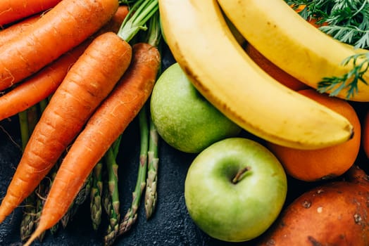 Healthy fruits and vegetables delivery from farm market. Organic food ingredients for diet vitamin smoothie recipe. Top view of superfood groceries, citrus, banana, asparagus, carrots, sweet potato and green apples. Colorful summer veggie background.