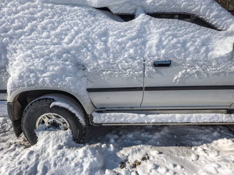 snow covered old white SUV car at sunny white winter day