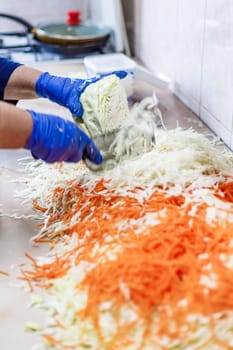 hands in blue gloves cutting cabbage with special double blade slit cabbage shredder knife during sauerkraut preparation