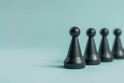 A black chess piece is standing in front of four other black chess pieces. The chess piece is the only one that is not in a line