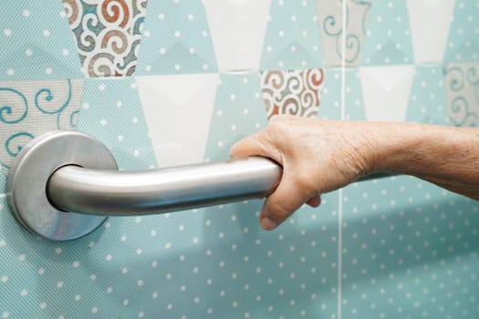 Asian elderly old woman patient use toilet support rail in bathroom, handrail safety grab bar, security in nursing hospital.