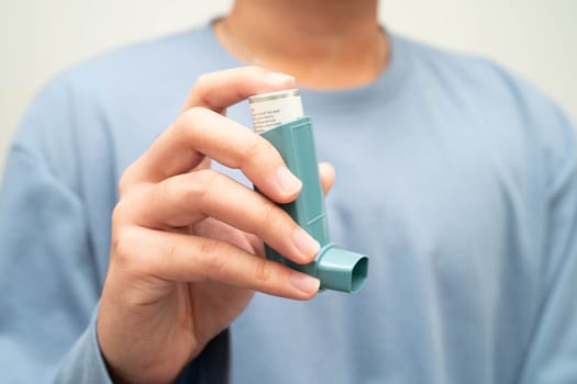 Asthma and chronic obstructive pulmonary disease COPD, Asian young man using metered dose inhaler MDI.
