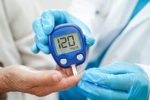 Asian doctor using digital glucose meter for check sample blood sugar level to treatment diabetes.