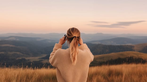 Woman with binoculars appreciating a breathtaking mountain landscape at sunset, capturing natures beauty.
