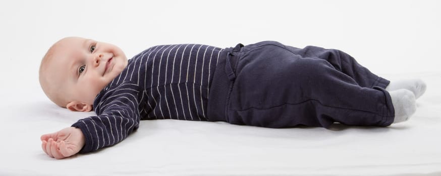 smiling toddler in blue clothing laying down. vertical image