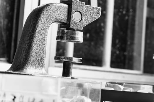 Black-and-white shot of a textured metal press used in watchmaking, emphasizing the tool's role in ensuring delicate, even pressure for wristwatch case closure