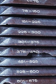 Plastic drawers labeled with number ranges serve as a storage system. Aged and worn with rust, the setup implies frequent use, each drawer organized for quick access to categorized items
