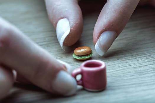Tiny burger and coffee illustrate correct nutritional portions. Though visually appealing, their minuscule size highlights the challenge of adapting to portion control as advised by dietitians