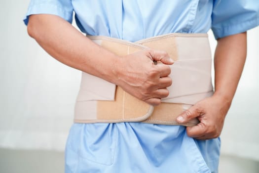 Asian senior wearing elastic support belt can help reduce back pain.