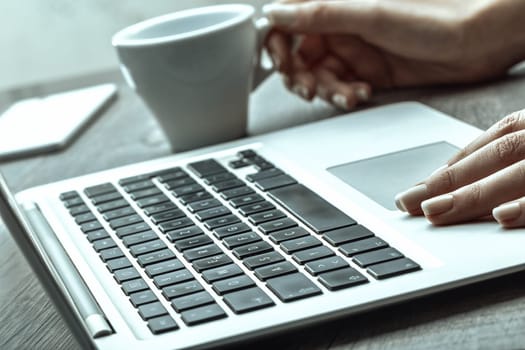 Image features a hand with polished nails on a laptop keyboard, with a coffee cup in the blurred background, evoking a serene, productive workspace vibe