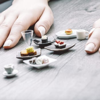 Miniature servings of coffee, pastries, and sushi illustrate portion control's tension between satisfaction and discipline. These visually appealing foods feel almost impossibly small