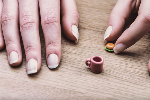 Miniature burger and coffee cup showcase the difficulty of portion control. Although correct, their size visually represents the struggle of adjusting to recommended dietary portions.