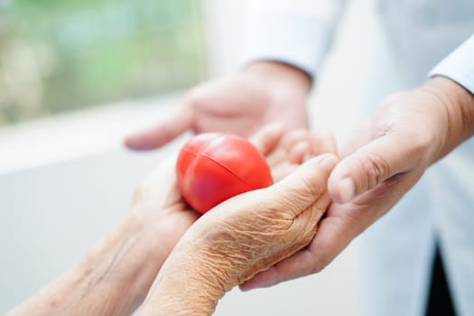 Asian man doctor give red heart to elderly woman patient for good health in hospital.