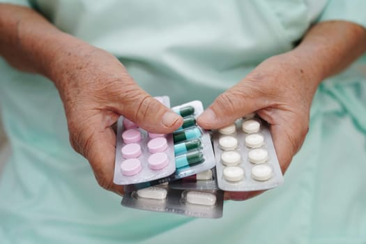 Asian elderly woman holding pill drug in hand, strong healthy medical concept.