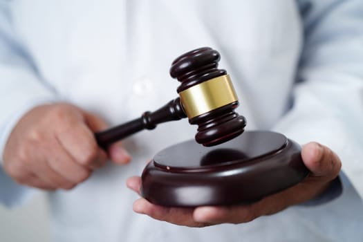 Asian doctor holding court hammer for and crime law justice, forensic medicine.