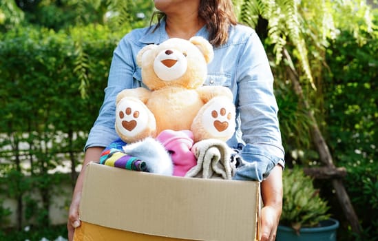 Volunteer collect cloth and doll in cardboard box to donate.