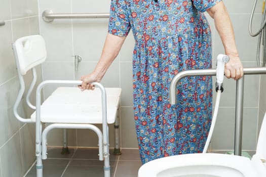 Asian elderly old woman patient use toilet support rail in bathroom, handrail safety grab bar, security in nursing hospital.