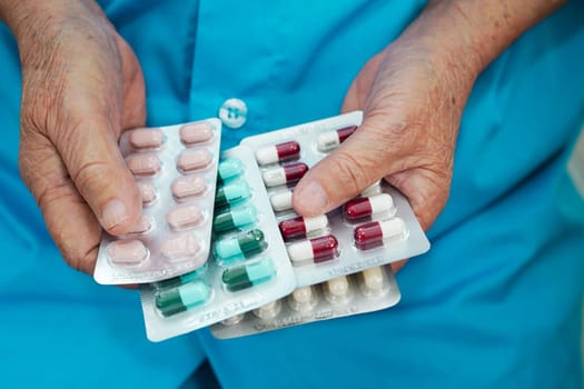 Asian elderly woman holding pill drug in hand, strong healthy medical concept.