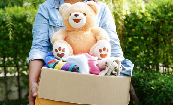 Volunteer collect cloth and doll in cardboard box to donate.
