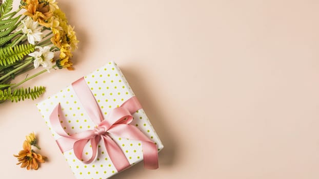 white yellow flower bouquet near wrapped present box peach surface. Resolution and high quality beautiful photo