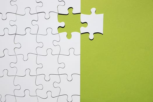 white puzzle piece separate with white puzzle grid green backdrop. Resolution and high quality beautiful photo