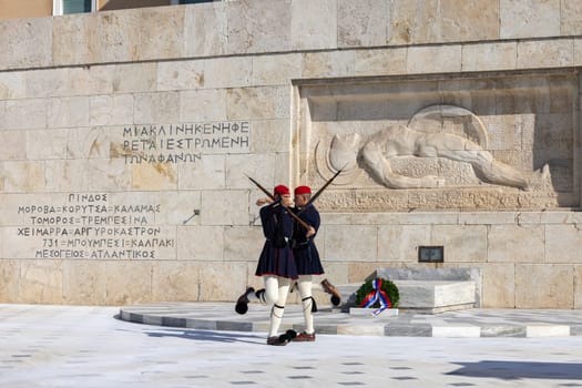 Athens, Greece - October 19, 2022: Changing of the Guard in front of Greek Parliament (Old Royal Palace) by Evzones, Greek representative military formation. On a background Tomb of Unknown Soldier.