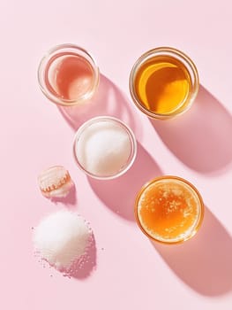 Overhead view of sugar and honey in glass jars on a pink background, highlighting sweet indulgence.