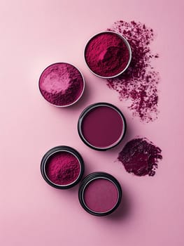 Bold pink makeup powders in small containers, spread artistically on a pink background, ideal for beauty and cosmetics.
