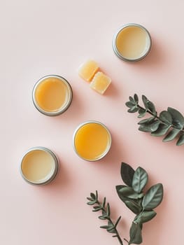 Jars of natural lip balm with leaves on a pink background, ideal for skincare and beauty enthusiasts.